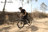 Rugged Blutron Mountain Ebike - Rider navigating this off-road electric bicycle along a rocky dirt trail in a sunlit outdoor landscape