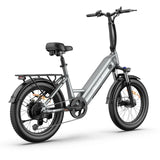 Blutron compact folding electric bike for urban daily commutes: Silver-gray model featuring "BLUTRON" logo, rear cargo rack, wide slip-resistant tires, front/rear disc brakes, handlebar controls, and a black seat, displayed against a clean white background.